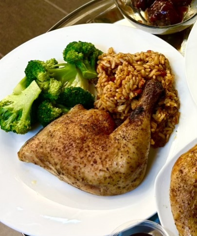 Plated catering dish with seasoned chicken, rice, and steamed broccoli on a white plate.