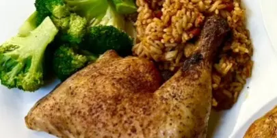Plated catering dish with seasoned chicken, rice, and steamed broccoli on a white plate.