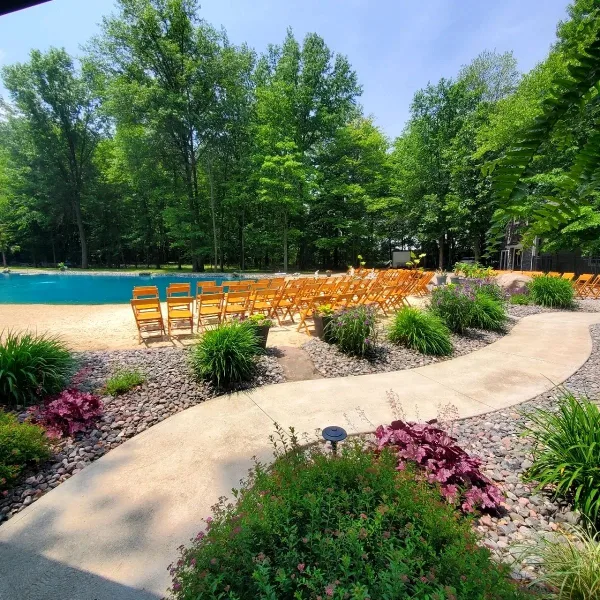 Outdoor wedding ceremony setup with wooden chairs arranged near a pond and forest.
