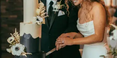 A bride and groom cutting a multi-tiered black and white wedding cake with floral decorations.