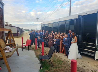 A wedding party posing next to a white party bus