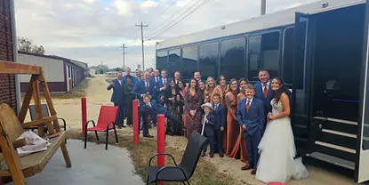 A wedding party posing next to a white party bus