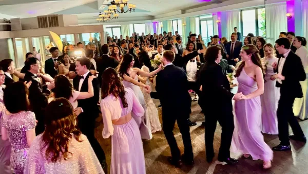 A crowded wedding dance floor with guests dancing at a reception.