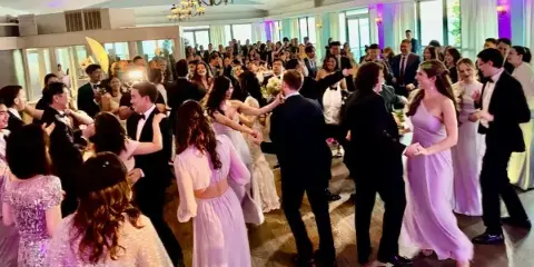 A crowded wedding dance floor with guests dancing at a reception.