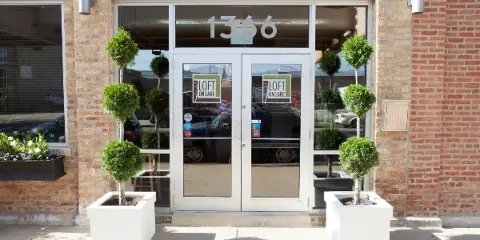 Exterior view of the Loft on Lake venue entrance featuring glass doors, brick walls, and topiary planters.