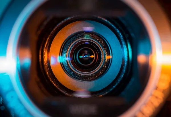 Close-up view of a camera lens with blue and orange reflections