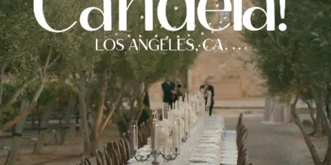 A long wedding reception table set outdoors with string lights and musicians performing in the background.
