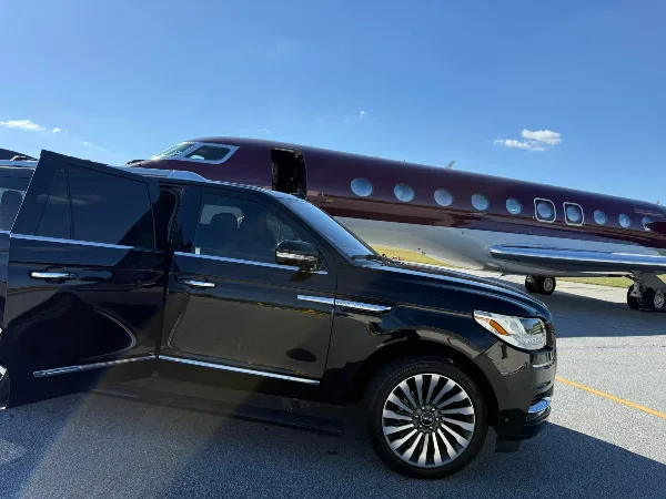 Black luxury SUV parked on an airport tarmac next to a private jet