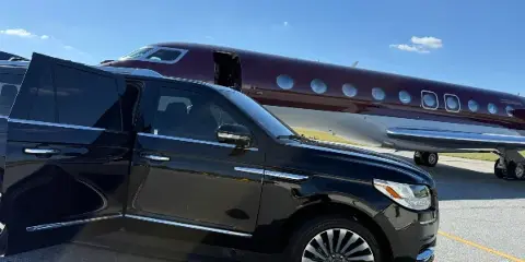Black luxury SUV parked on an airport tarmac next to a private jet