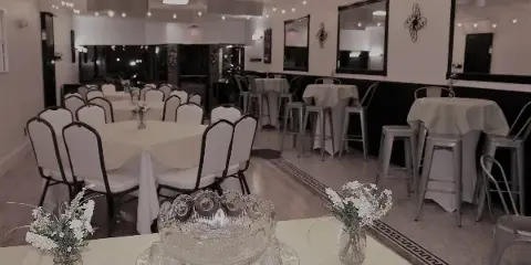 Interior view of an event venue with white tablecloths, chairs, and string lights.