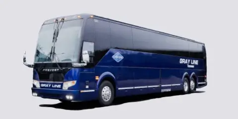 A blue Gray Line motorcoach bus parked against a white background.