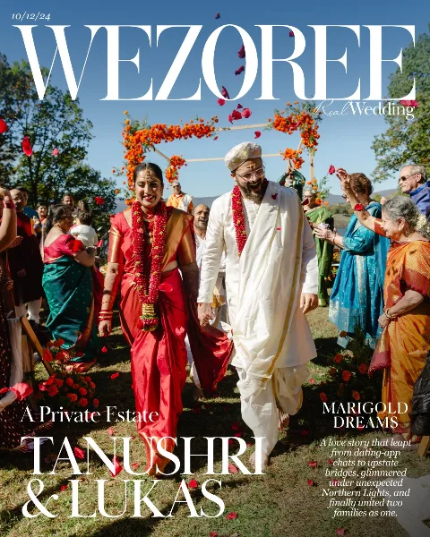 A couple in traditional Indian wedding attire walking through a crowd at an outdoor wedding reception, featured on a Wezoree magazine cover.