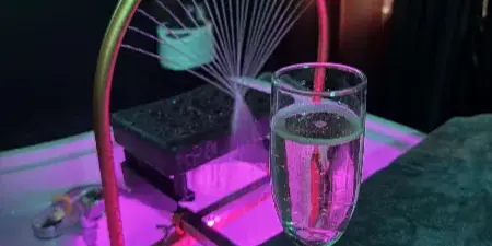 Interior view of a beauty salon showing a treatment chair, a glass of champagne, and a towel under purple ambient lighting.