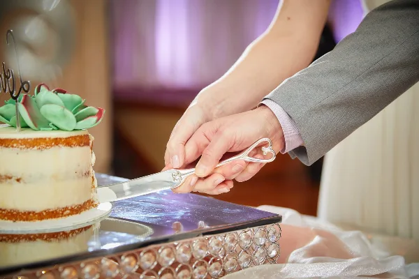 A bride and groom cutting a wedding cake together at a reception.