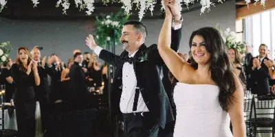 A bride and groom dancing under a large hanging floral installation in a wedding venue.