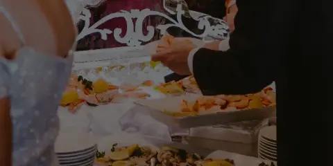 A catering staff member serving shrimp and oysters from a buffet station at an event.