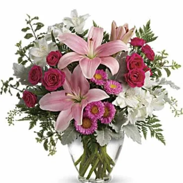 A floral arrangement with pink lilies, red roses, and white alstroemeria in a clear glass vase.