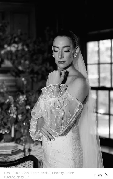 Black and white portrait of a bride with styled hair, makeup, and veil in a venue setting, representing bridal hair and makeup services.