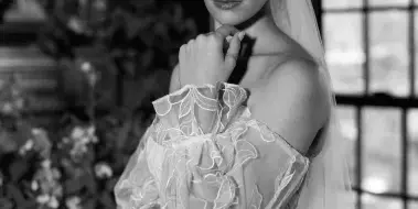 Black and white portrait of a bride with styled hair, makeup, and veil in a venue setting, representing bridal hair and makeup services.
