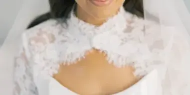 Portrait of a smiling bride wearing a white lace wedding dress and veil.