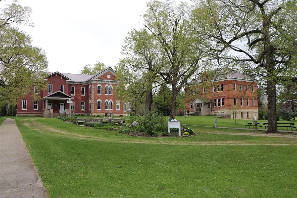 Exterior view of the historic Lenox College campus featuring red brick buildings and a green lawn.