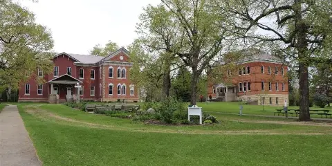 Exterior view of the historic Lenox College campus featuring red brick buildings and a green lawn.