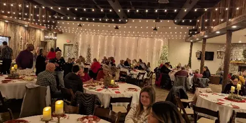 Interior view of the event center with round tables, string lights, and guests seated.