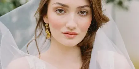 Portrait of a bride with natural makeup and loose, wavy hair wearing a veil.