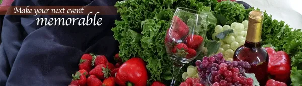 Catering food display with lettuce, strawberries, grapes, red peppers, and a wine bottle