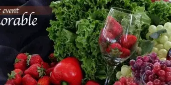 Catering food display with lettuce, strawberries, grapes, red peppers, and a wine bottle
