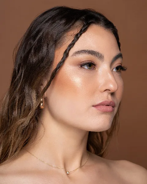 A professional beauty portrait of a woman with a braided updo hairstyle and natural makeup.