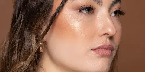 A professional beauty portrait of a woman with a braided updo hairstyle and natural makeup.