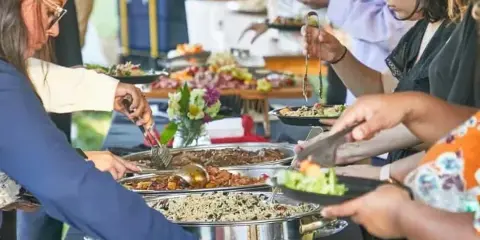Guests serving themselves food from a buffet line at a catering event.
