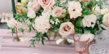 Styled event table with floral centerpiece, pink linens, glassware, and place settings