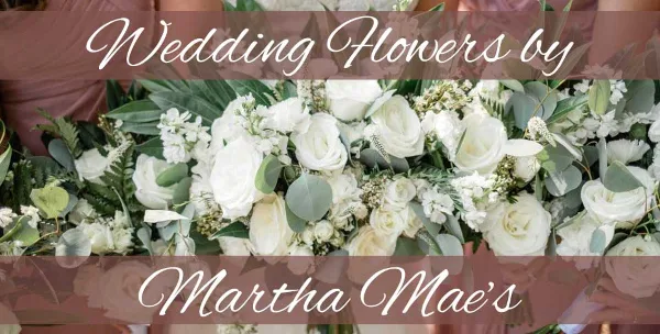 A close-up photograph of a white rose and eucalyptus wedding bouquet with text overlay reading 'Wedding Flowers by Martha Mae's'.