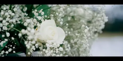 Close-up of a white rose and baby's breath wedding bouquet.