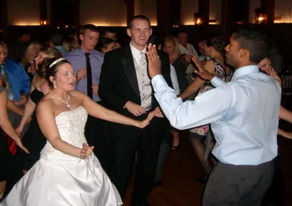 A bride and groom dancing at a wedding reception with other guests in the background.