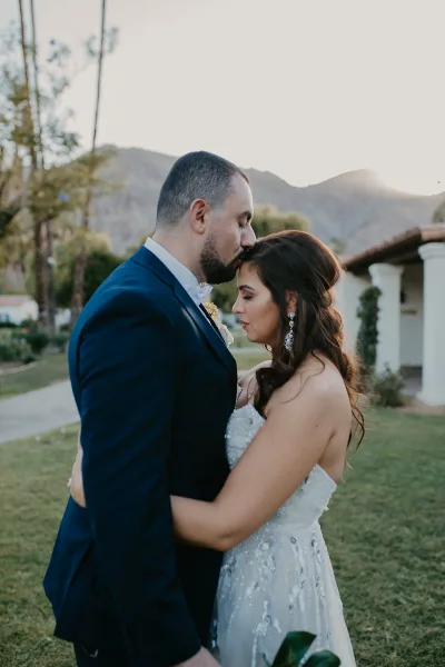 A close-up of a bride and groom, highlighting the bride's styled hair and makeup.