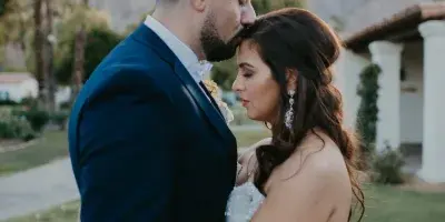 A close-up of a bride and groom, highlighting the bride's styled hair and makeup.