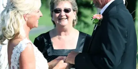 A wedding officiant presiding over a couple exchanging rings during a ceremony.