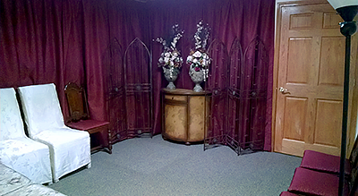 Interior view of a small wedding chapel office with white chairs, a decorative screen, and floral arrangements.