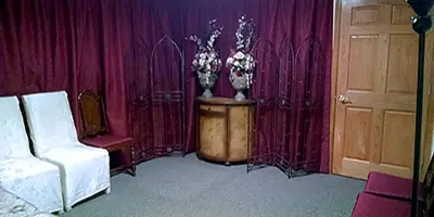Interior view of a small wedding chapel office with white chairs, a decorative screen, and floral arrangements.