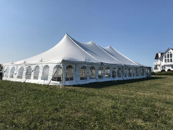 A large white event tent with arched windows set up on a grassy lawn.