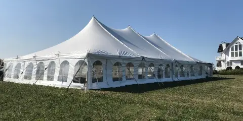 A large white event tent with arched windows set up on a grassy lawn.