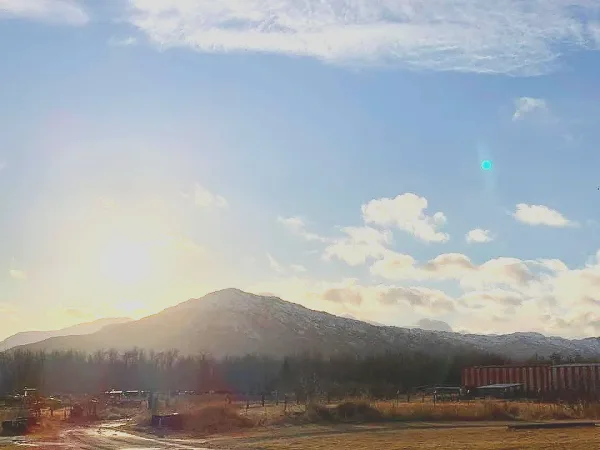 Exterior view of the Kodiak Island Fairgrounds arena and grounds with mountains in the background.