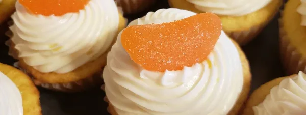 Close-up of cupcakes with white frosting and orange candy toppings