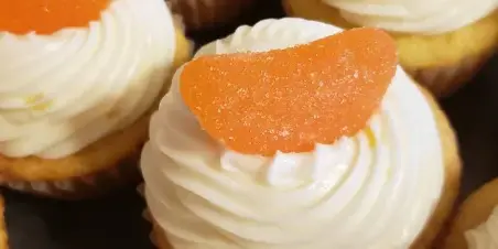 Close-up of cupcakes with white frosting and orange candy toppings