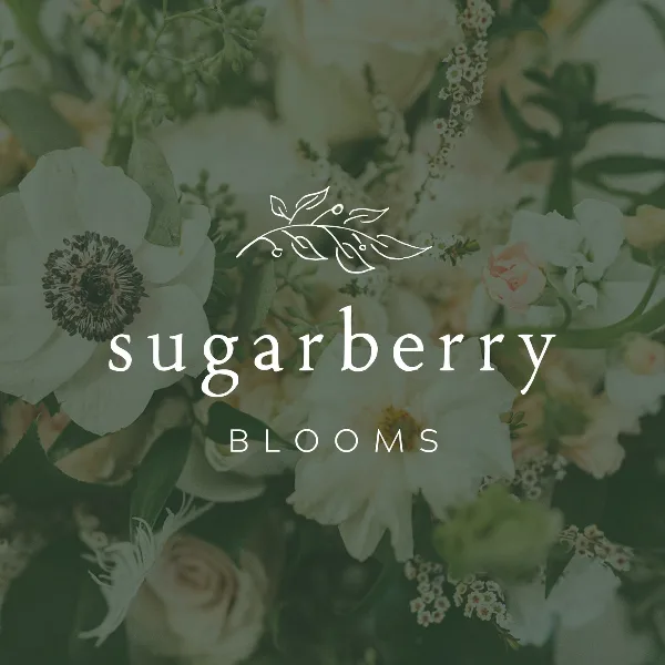 A close-up photograph of a lush floral arrangement featuring white peonies, soft pink roses, and greenery, with the Sugarberry Blooms logo overlaid.