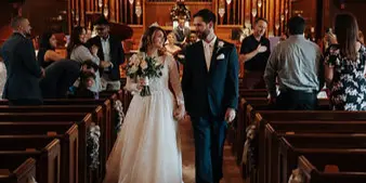 A bride and groom walking down the aisle of a church during a wedding ceremony.