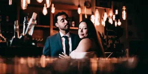 Cinematic portrait of a wedding couple in a dimly lit bar with Edison lights.